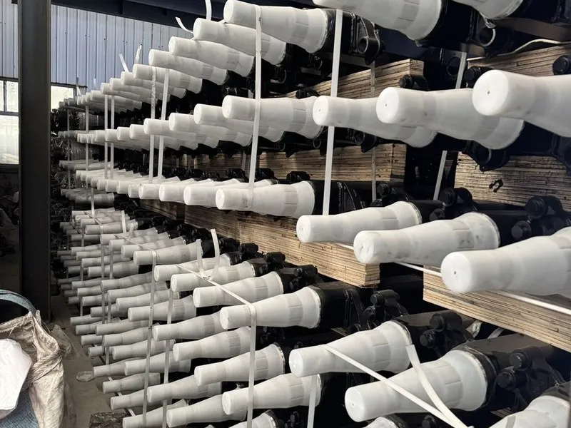 Trailer axle beams with protective end caps racked in stock