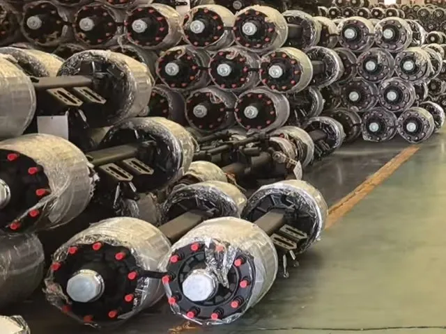 Trailer axles with wrapped brake drums and capped hub ends stacked in stock