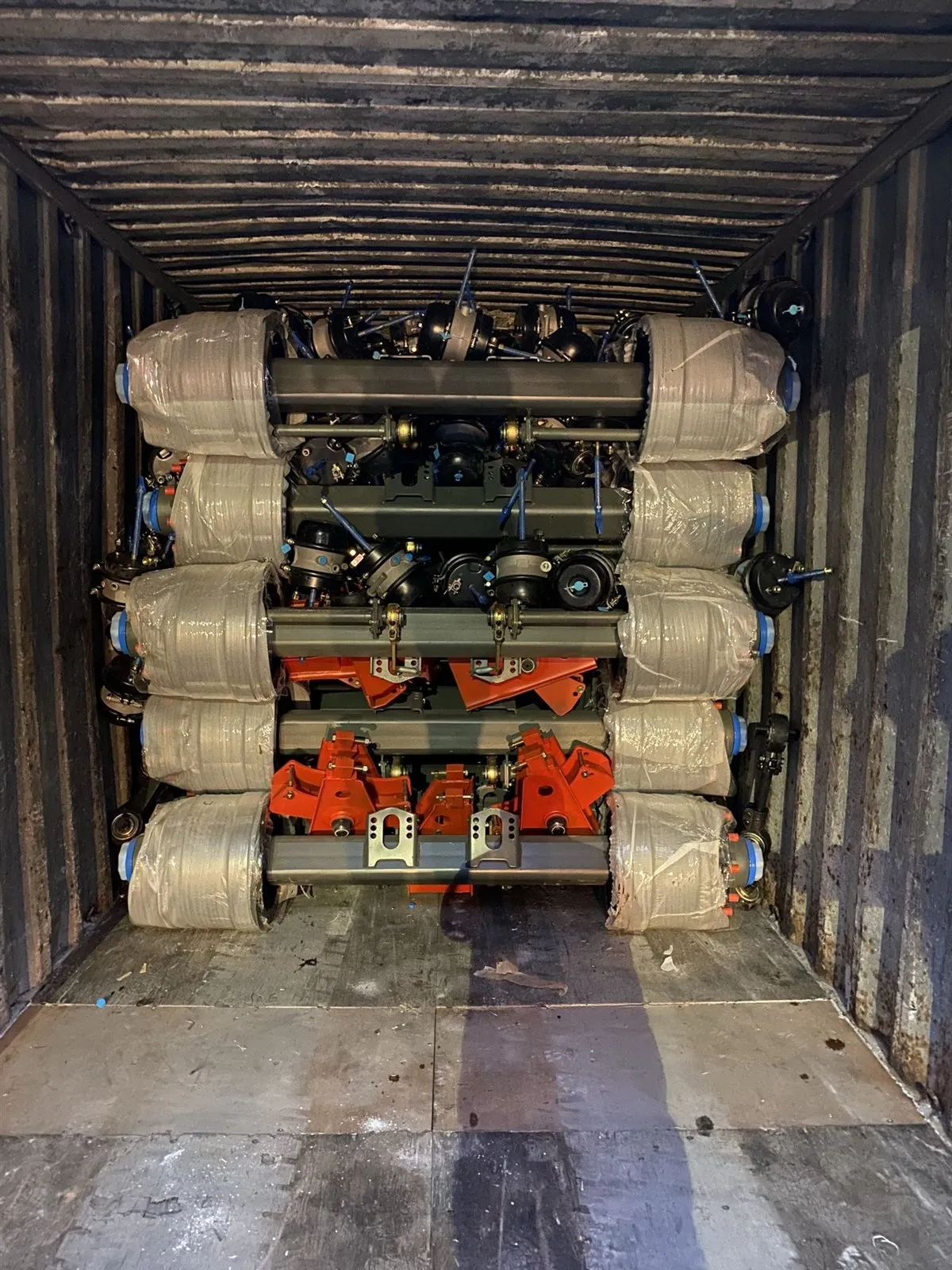 Axle and suspension assemblies loaded and secured in layers inside a shipping container